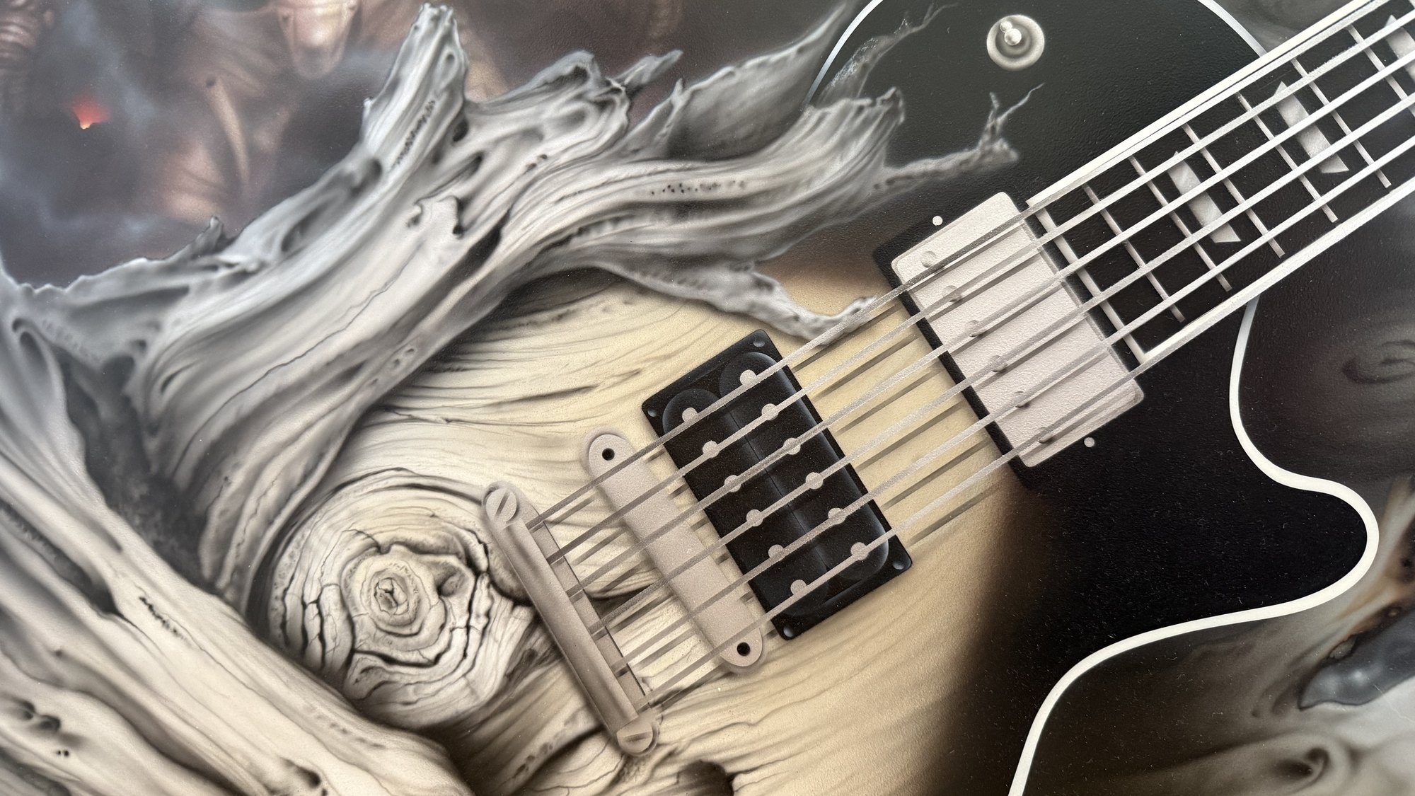 A black Les Paul lying in bleached fallen timber