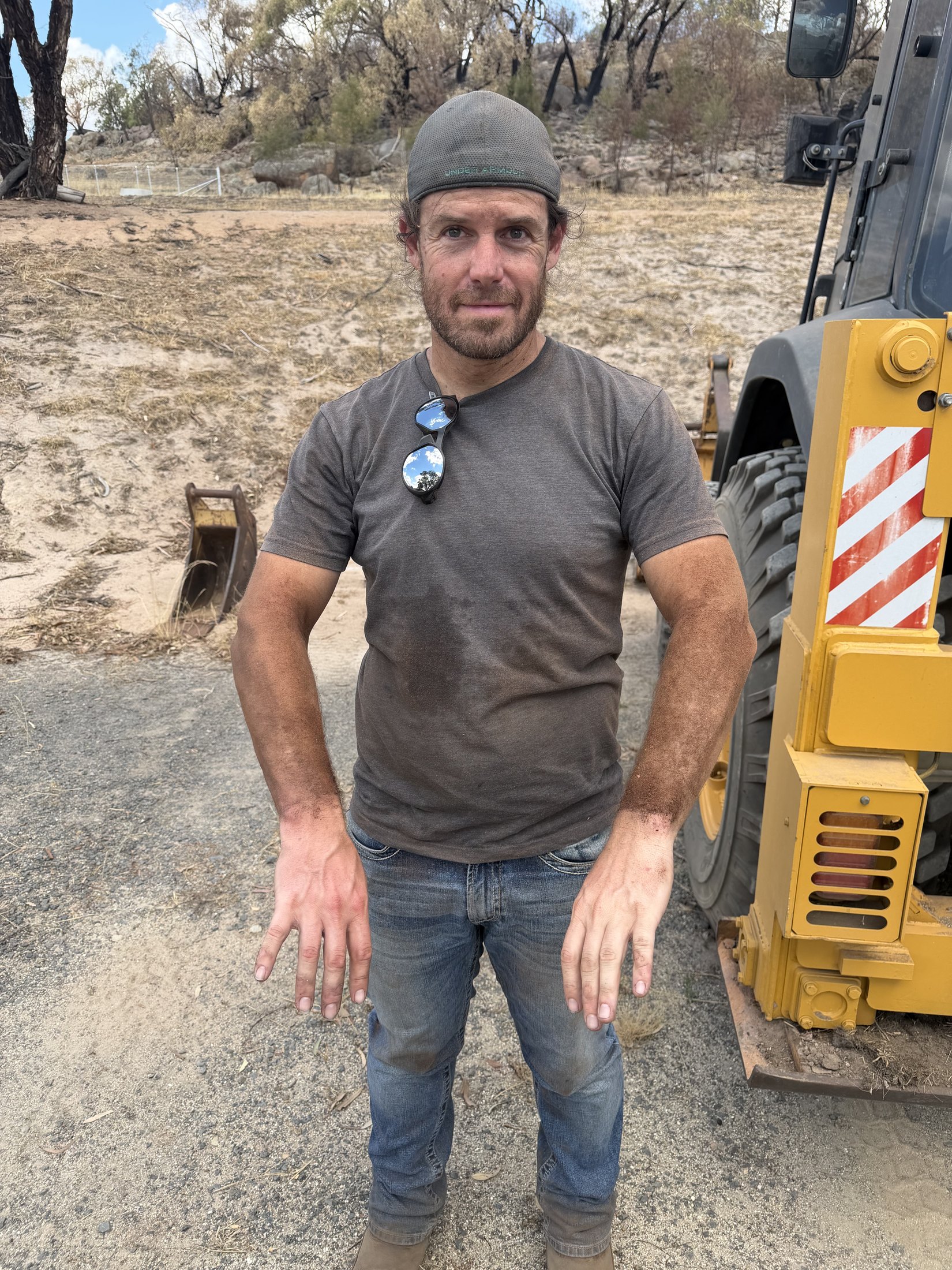 Mark Follett covered in dust beside a loader after a day of earthworks